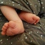 Baby feet on a gray blanket