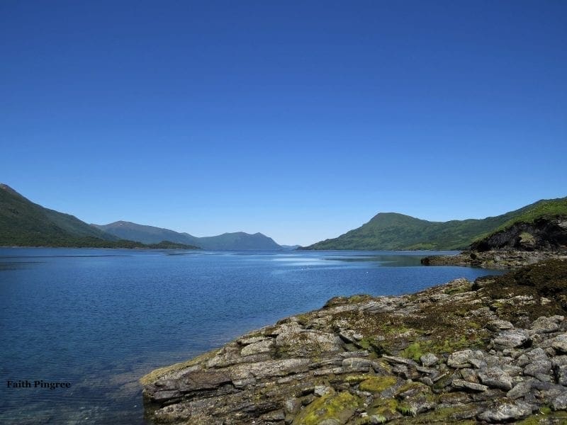 Alaskan bay with rocky shore and distant mountains, photo credit Faith P.
