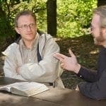 Two men with an open Bible outdoors, one is skeptically listening to the other: Photo 1302675 © Kenneth Sponsler - Dreamstime.com