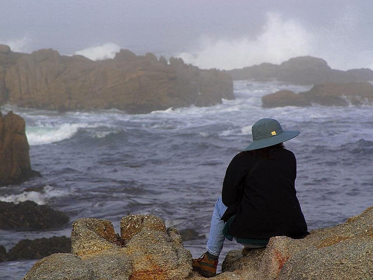 Woman in hat overlooking a rainy sea, photo credit: Pixnio